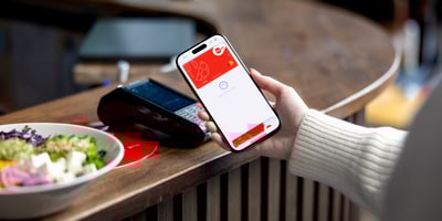 Nainen tekee lähimaksua puhelimella lounasravintolan tiskillä