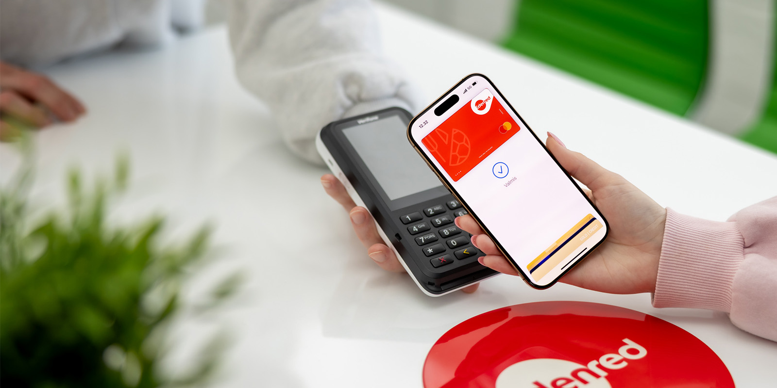 Nainen maksaa puhelimen Apple Paylla maksupäätteellä