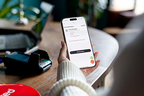 Nainen maksaa puhelimen sovelluksella Edenred Pay -mobiilimaksua kassalla