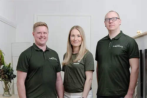 Kolme kiropraktikkoa vihreät työpaidat päällä