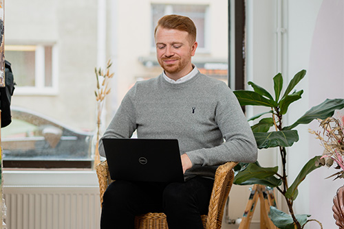 Mies istuu nojatuolissa ja työskentelee tietokoneella