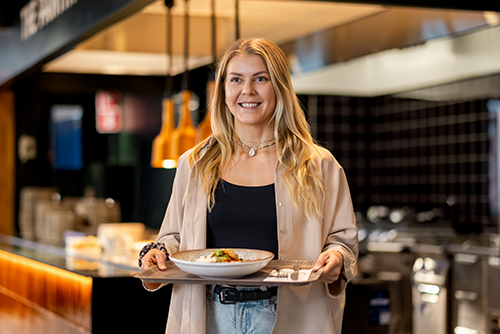 Smiling young woman carrying a tray with lunch portion at a restaurant