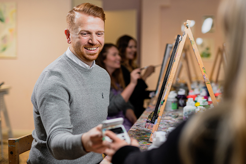 Man paying for his painting class with mobile phone