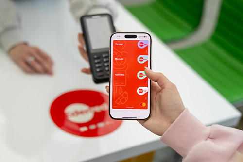 Woman holding a phone with Apple Wallet open with all the Edenred payment cards added to it
