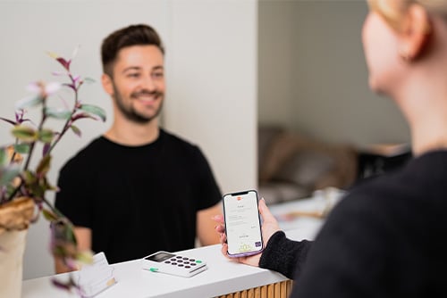 Mies kassalla ottamassa vastaan asiakkaan puhelimella tekemää Edenred Pay -mobiilimaksua