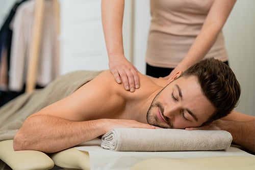 En ung man ligger på en massagebänk