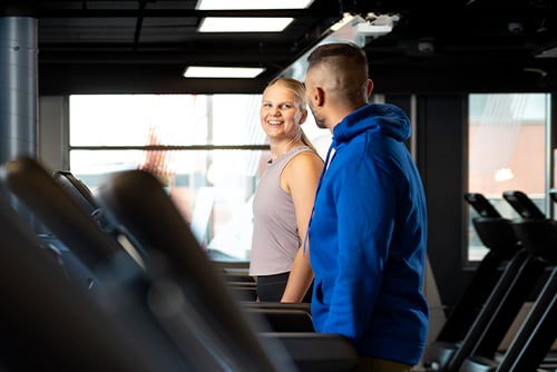 En man och en kvinna springer på ett löpband på ett gym